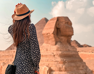 lady in floral dress and brown hat looking at the sphinx