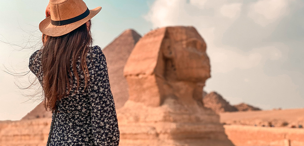 lady in floral dress and brown hat looking at the sphinx