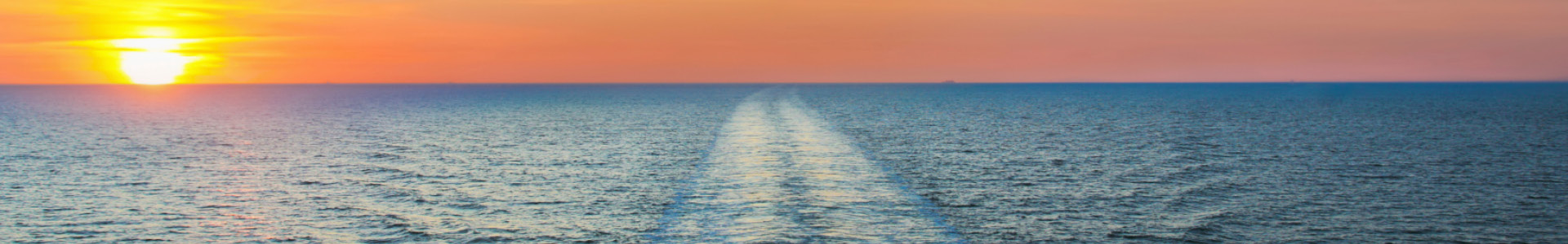Sunset over a tranquil ocean, with gentle waves creating a foamy wake, casting a warm glow across the water.