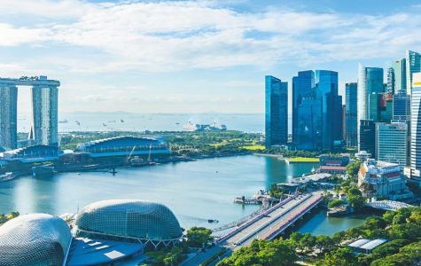 Panoramic view of Singapore’s Marina Bay, with Marina Bay Sands, domed Gardens by the Bay, skyscrapers, blue water, and bright skies.