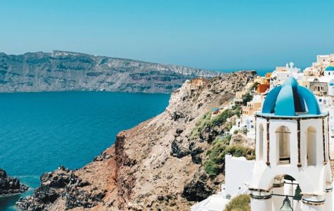 Bright, serene Santorini cliffside village with whitewashed buildings and blue domes overlooking the turquoise Aegean Sea and rugged caldera coast.