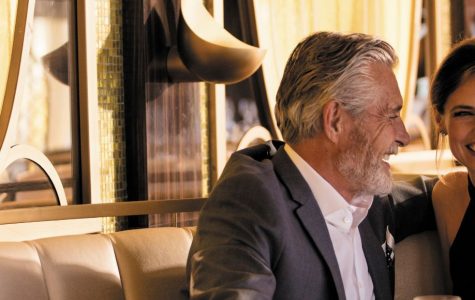 Smiling couple enjoying wine together in an elegant, sunlit train dining carriage, conveying warmth, romance, and relaxed luxury.