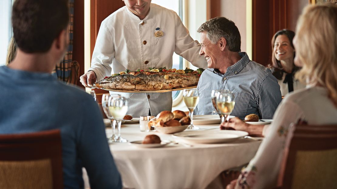 A group of diners enjoying a meal in an elegant restaurant setting, with beautiful arrangements and soft lighting.