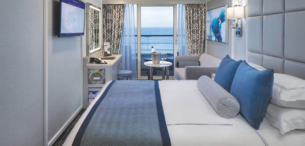 A modern stateroom featuring a king bed, balcony with ocean view, plush furnishings, and a flat-screen TV onboard the Oceania Regatta.
