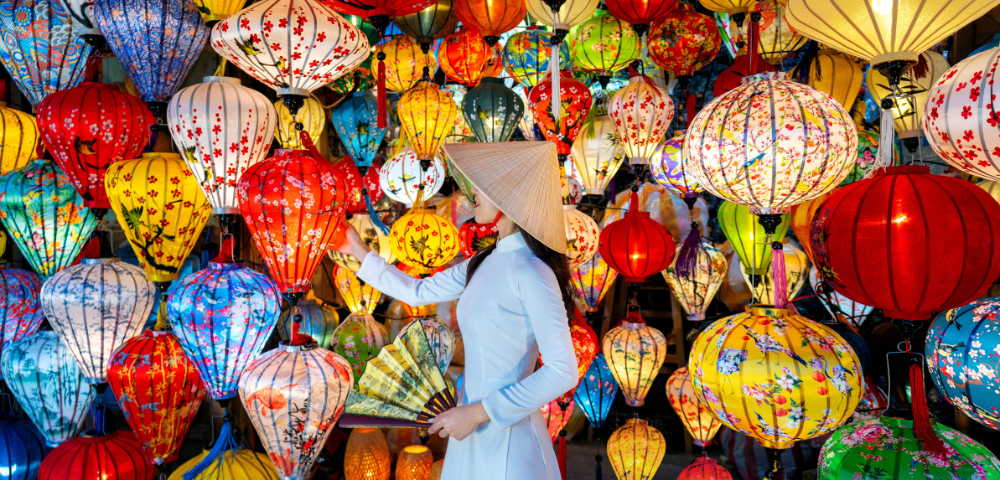A woman in traditional attire admires colorful lanterns in a vibrant display.