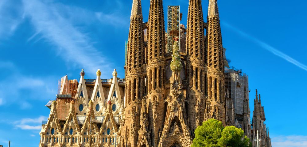 A grand cathedral with intricate gothic spires and detailed facades rises against a clear blue sky, evoking an architectural wonder and awe.