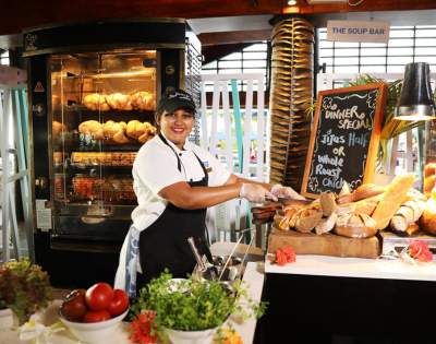 MYHOLIDAY-RADISSON-BLU-RESORT-FIJI-DENARU-ISLAND-WOMAN-BEHIND-COUNTER-CUTTING-BREAD-AND-SERVING-CHICKEN