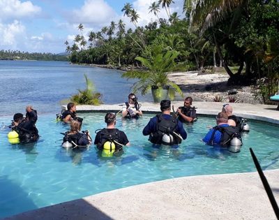 resort guests in pool in scuba diving gear with ocean in background