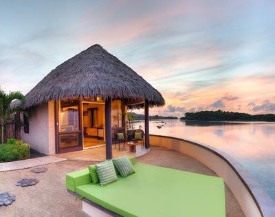 Green out door bed with villa in background and ocean views at sunrise