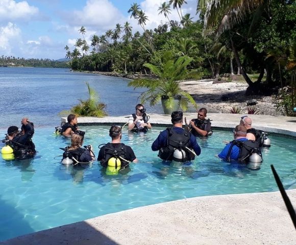 resort guests in pool in scuba diving gear with ocean in background