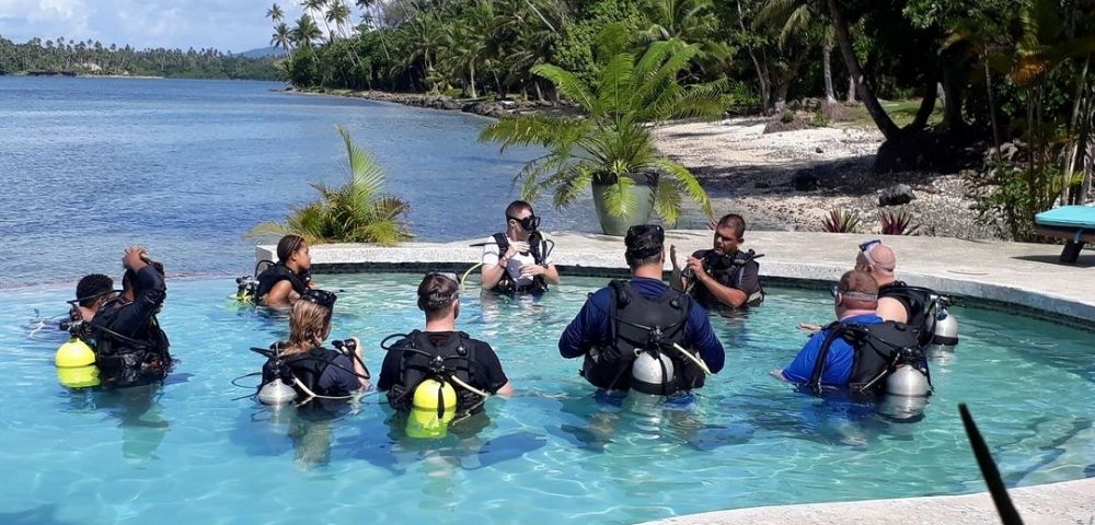 resort guests in pool in scuba diving gear with ocean in background