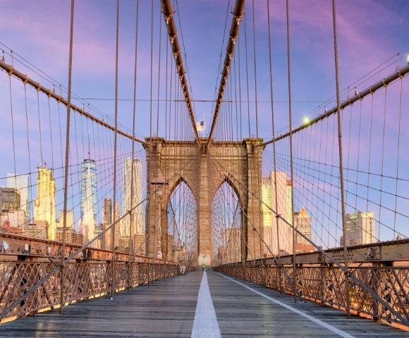 Sunset view on Brooklyn Bridge with New York City skyline in the background.