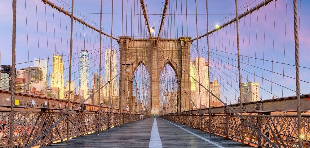 Sunset view on Brooklyn Bridge with New York City skyline in the background.