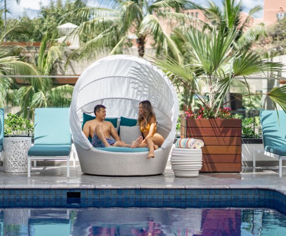couple sitting on pool lounge at Outrigger Waikiki Beachcomber Hotel in Hawaii