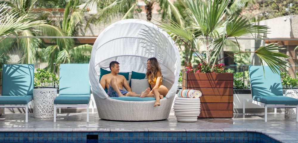couple sitting on pool lounge at Outrigger Waikiki Beachcomber Hotel in Hawaii