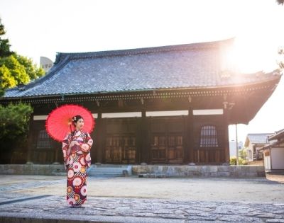 Image of Japanese lady in traditional clothing holding umbrella infront of building