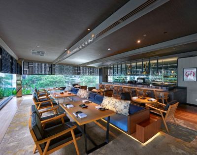 Restaurant seating area with table seating and bar seating and a view into the outside gardens and greenery