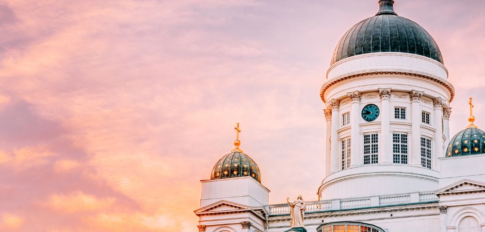 Dome of a classical building against a pastel sunset sky.