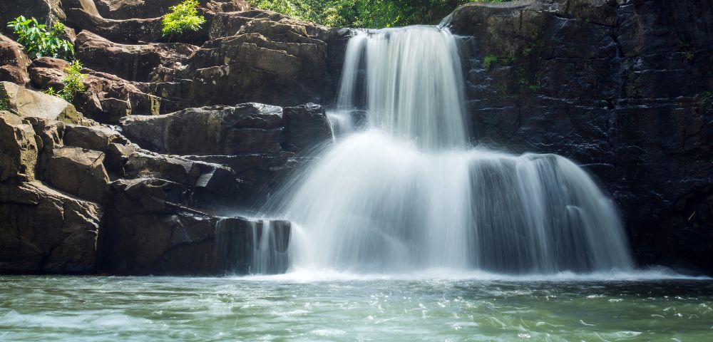 A tranquil waterfall cascading over rocks surrounded by lush greenery.