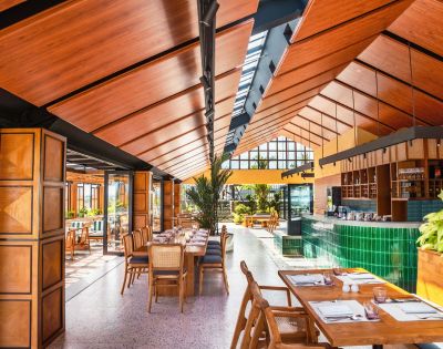 Elegant dining setup with rattan chairs and wooden tables in a bright restaurant.