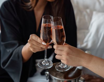 Two people toasting with glasses of rosé wine.