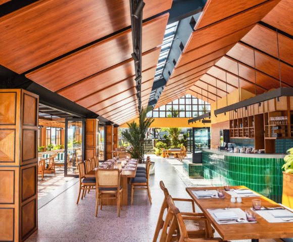 Elegant dining setup with rattan chairs and wooden tables in a bright restaurant.