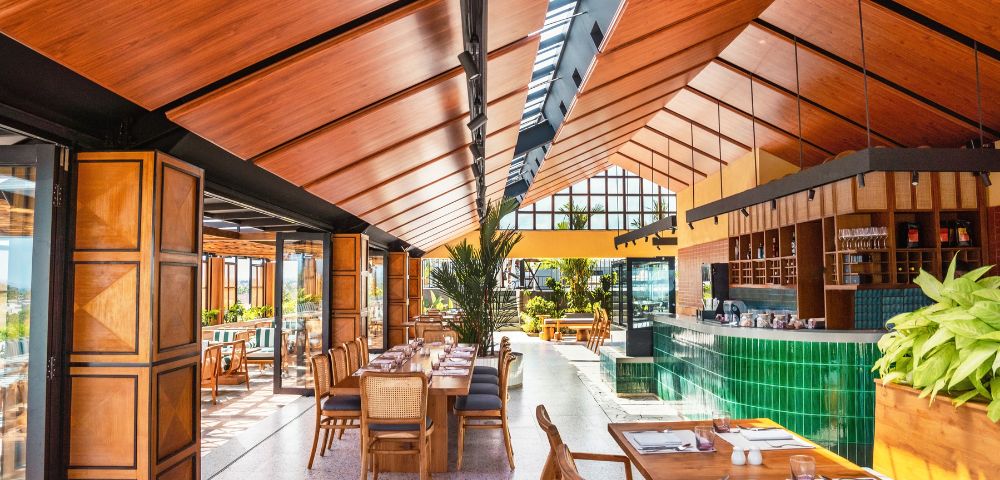 Elegant dining setup with rattan chairs and wooden tables in a bright restaurant.