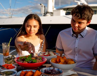 Two people dining outdoors with a spread of food on the table.