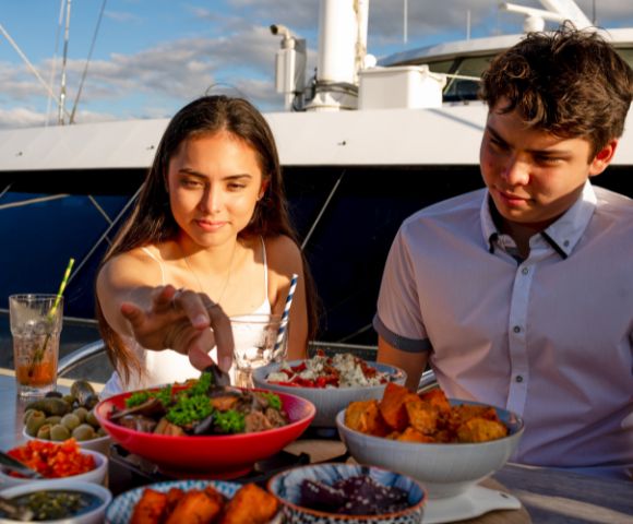 Two people dining outdoors with a spread of food on the table.