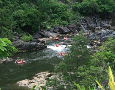 Rafting groups navigating through a rocky river surrounded by lush greenery.