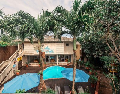 Tropical resort with a pool, surrounded by palm trees and a wooden deck.