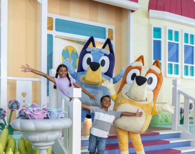 Bingo and Bluey with two kids on the house porch at Blueys World