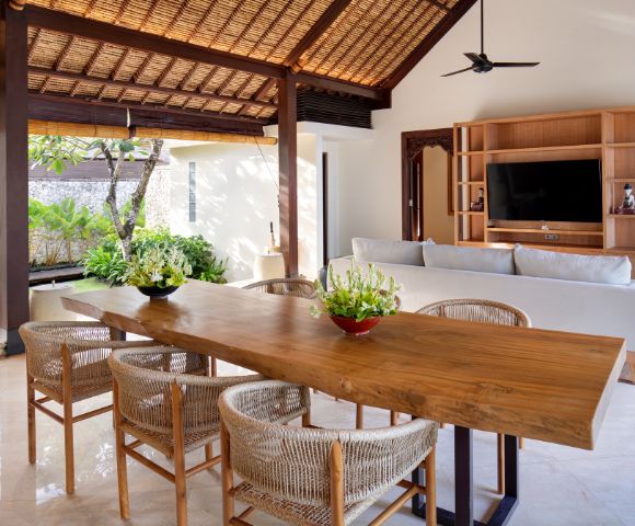 Elegant open living space with a wooden dining table, wicker chairs, and a white sofa under a vaulted ceiling.