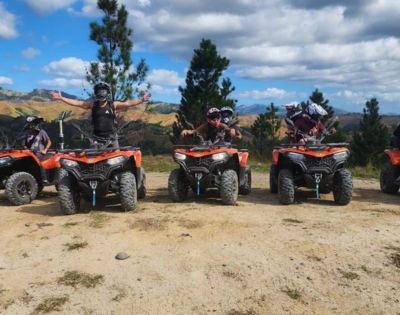 Group of people on ATVs outdoors, with one person celebrating arms outstretched.