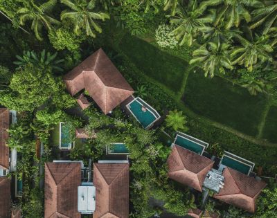 Aerial view of tropical resort with pools surrounded by lush greenery.