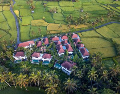 Aerial view of tropical resort with pools surrounded by lush greenery.