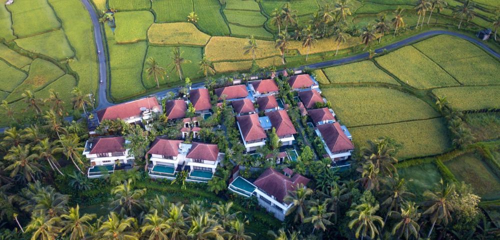 Aerial view of tropical resort with pools surrounded by lush greenery.