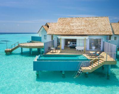 Overwater bungalow with a pool on a clear blue sea.