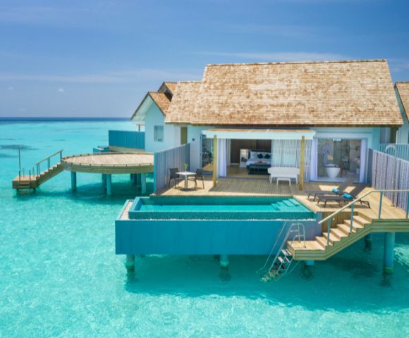 Overwater bungalow with a pool on a clear blue sea.