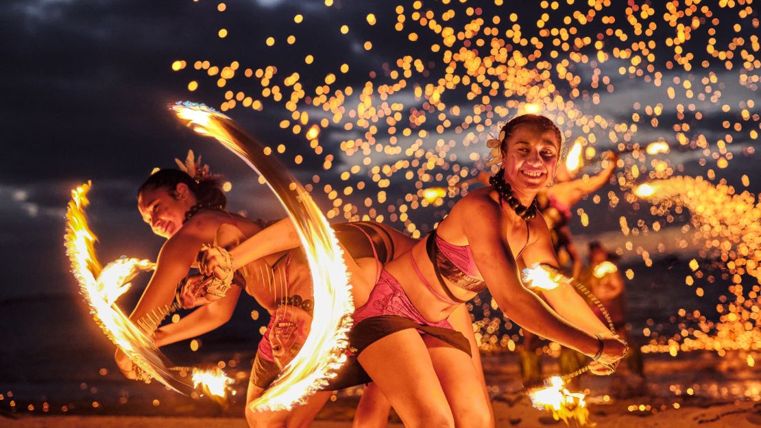 Crowne Plaza Fiji Nadi Bay Resort and Spa Performers twirling fire poi on a beach at night, with sparks flying around.