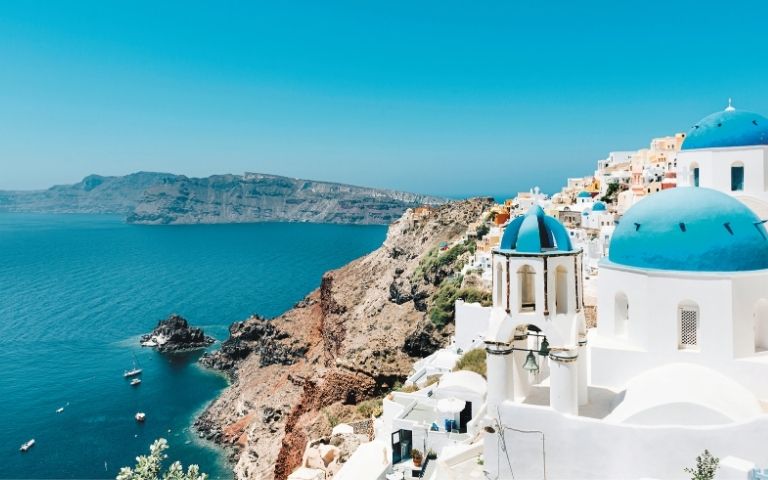 White buildings with blue domes in Santorini, Greece, overlooking the Aegean Sea.