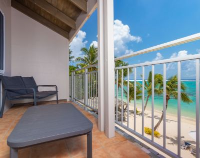 Balcony with a chair overlooking a tropical beach with palm trees and clear blue sea at Moana Sands Beachfront Hotel by My Holiday.
