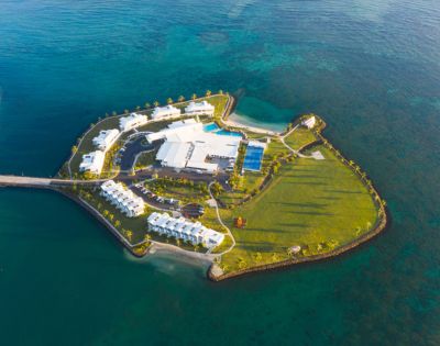 Aerial view of a resort on a small island surrounded by turquoise waters. Taumeasina Island Resort, Samoa.