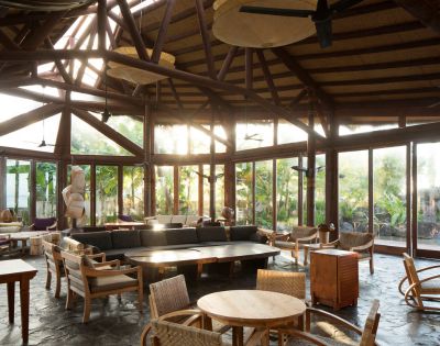 Sunlit tropical resort lounge with wicker furniture and wooden beam ceiling. Coconuts Beach Club Resort and Spa, Samoa.