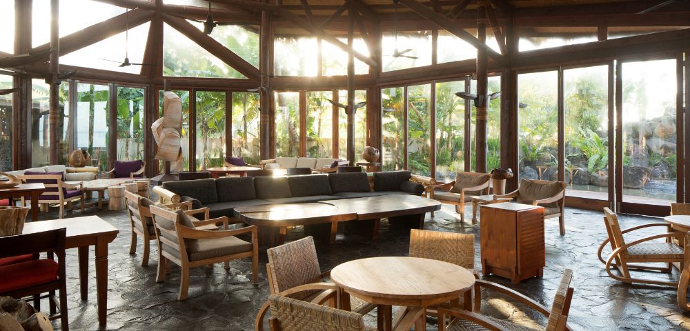 Sunlit tropical resort lounge with wicker furniture and wooden beam ceiling. Coconuts Beach Club Resort and Spa, Samoa.