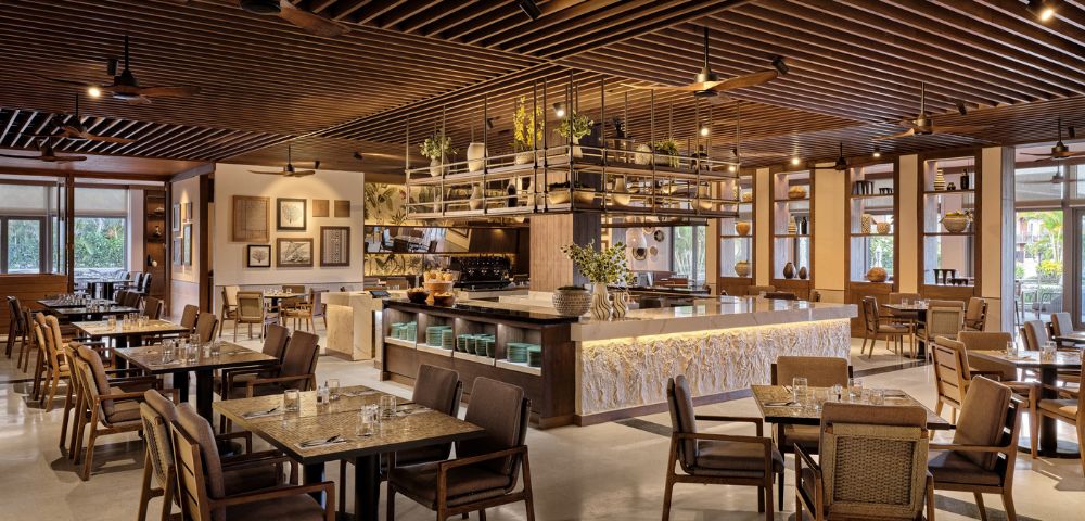 Elegant café interior with wooden tables, chairs, bar counter, pendant lights, and decorative ceiling.