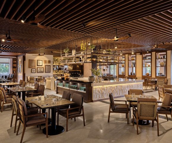 Elegant café interior with wooden tables, chairs, bar counter, pendant lights, and decorative ceiling.