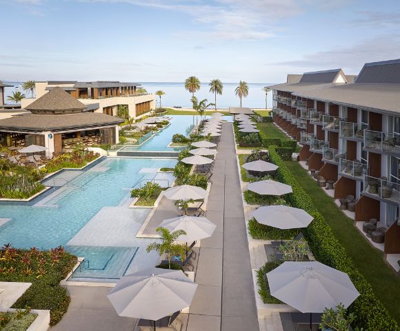 Luxury resort with swimming pools, umbrellas, loungers, and palm trees.