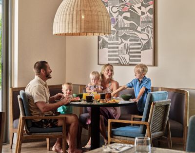 Family with two kids dining at a table in a modern restaurant with abstract art on the wall.