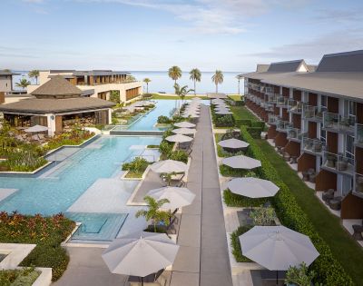 Luxury resort with swimming pools, umbrellas, loungers, and palm trees.